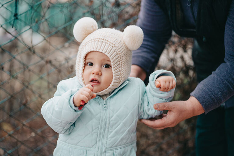 Um bebê branco com touca de lã e casaco de frio.